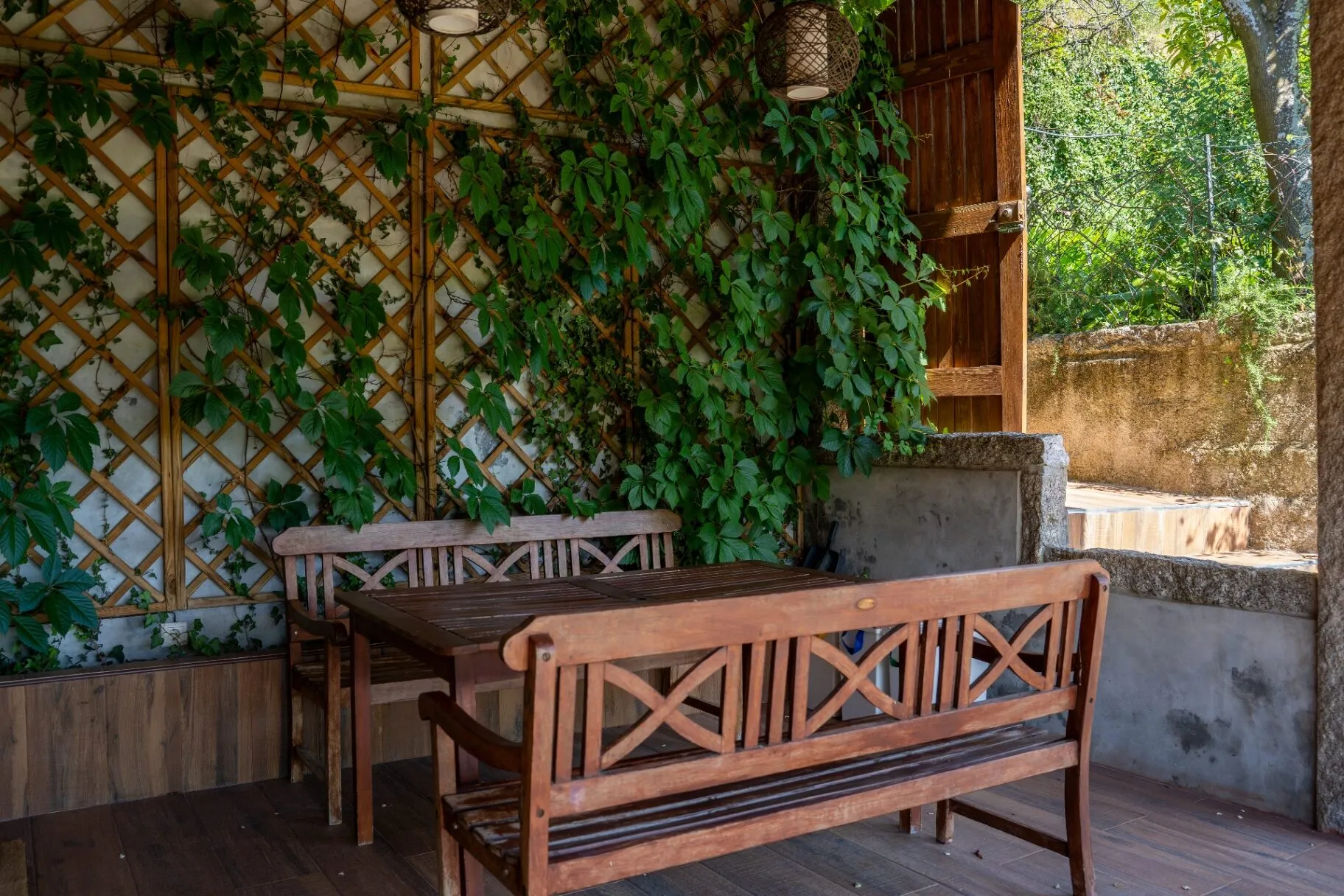 Pátio exterior com mesa rodeada de trepadeiras